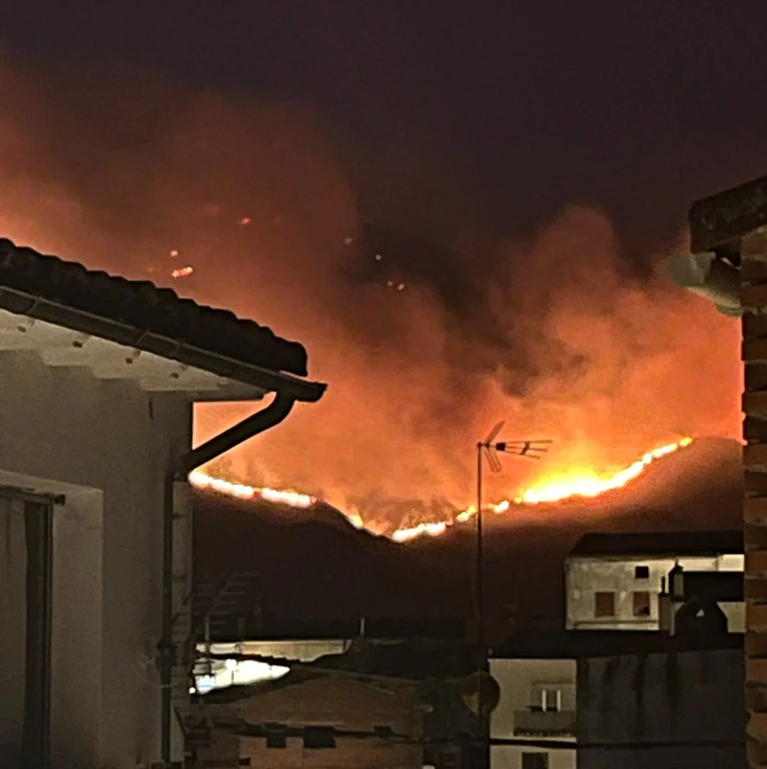 Paisaje calcinado con árboles quemados y brigadistas trabajando en un gran incendio forestal en Ávila